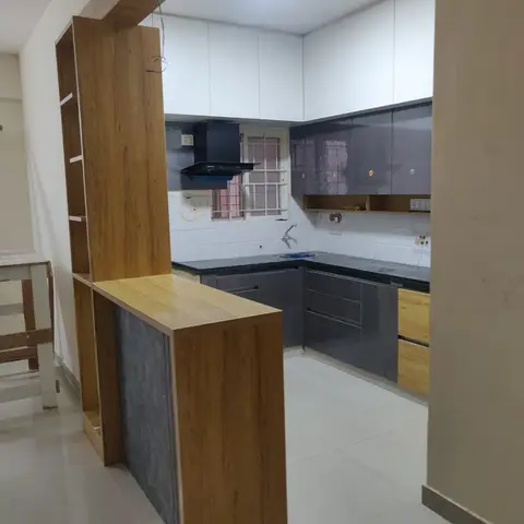 L-shaped modular kitchen with high-gloss charcoal-grey shutters and black granite counters