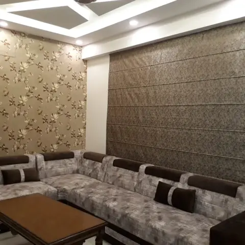 L-shaped sectional sofa living room with a floral gold-and-brown wallpaper accent wall, an angular cove-lit POP ceiling