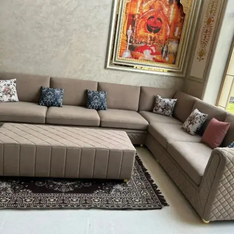 Large beige suede L-sofa with diamond-quilted arms and a matching quilted ottoman on a maroon Persian rug