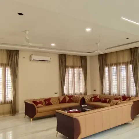 Large living room with tufted tan-and-maroon leather L-shaped sofas facing a matching sofa across a marble floor