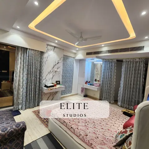 Large master bedroom with a diamond-shaped cove-lit false ceiling, a marble-clad accent wall with a built-in dressing counter