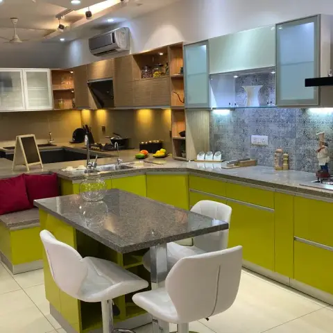 Lime-green high-gloss kitchen wrapping a granite breakfast island with white swivel chairs