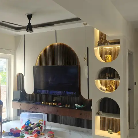 Lived-in living room where a charcoal fluted wall carries a backlit arch behind the TV and a freestanding white partition holds three lit arched niches of