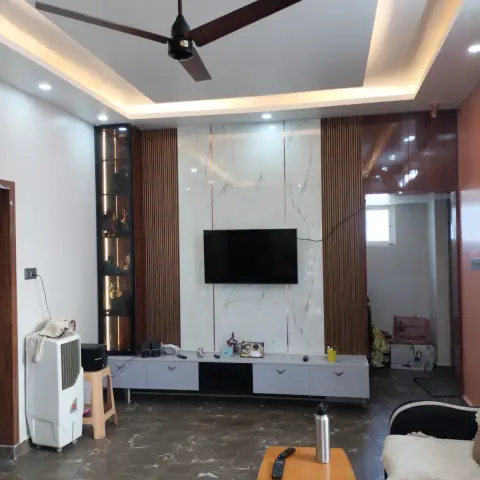 Lived-in living room whose TV wall pairs a white marble-look slab with walnut fluted panels and a backlit black glass curio column