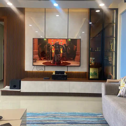 Lived-in living room with a stone-clad TV feature wall flanked by vertical fluted wood panelling and a glass-fronted display cabinet