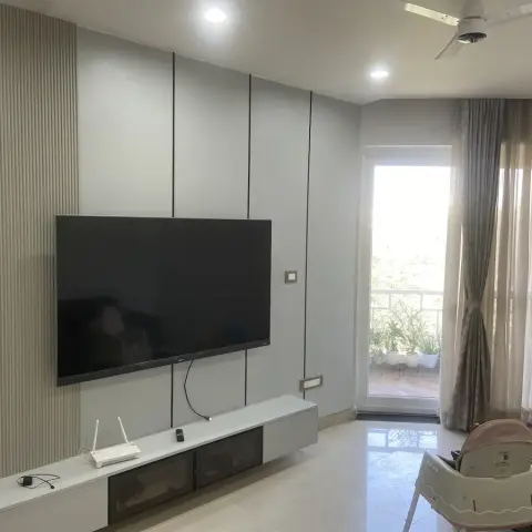 Lived-in living room with a pale grey grooved-and-fluted TV panel wall, a wall-hung white console holding a router