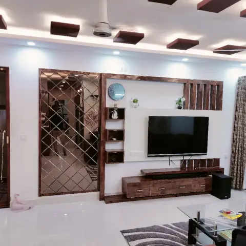 Lived-in living room with a walnut-framed TV unit, stepped display boxes and a batten screen, beside a full-height bevelled diamond mirror panel