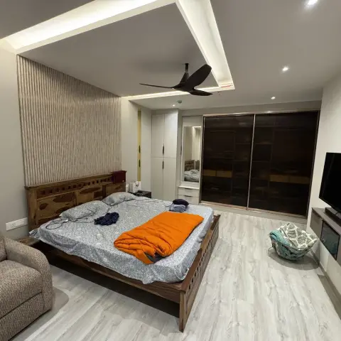 Lived-in master bedroom with a solid sheesham bed standing against a beige fluted panel