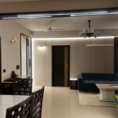 Living area lit by a continuous LED profile trim along the archway, with a navy sofa