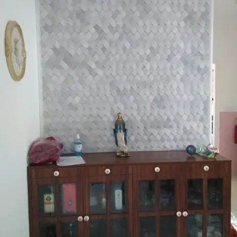 Living/dining feature wall with a 3D basket-weave stone tile accent above a wood crockery cabinet with glass-paned doors displaying glassware and bottles