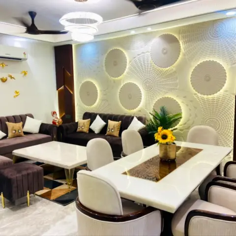 Living-dining hall with a marble-top six-seater against a backlit wall of white 3D carved discs