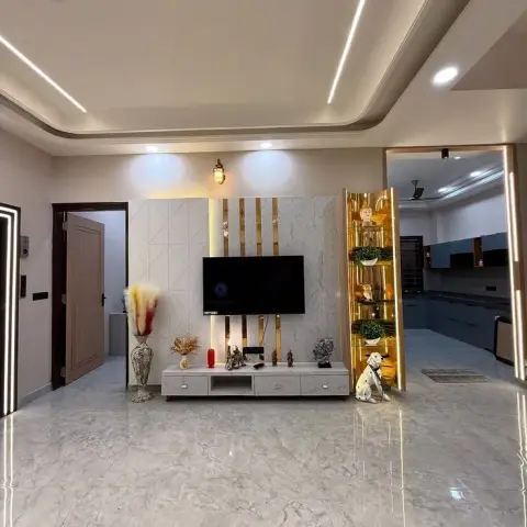 Living hall TV wall in marble-look slab cladding banded with gold strips, flanked by a backlit gold-mirror display tower