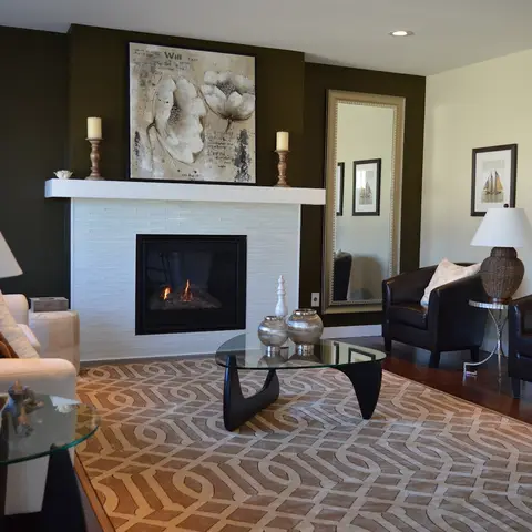 Living room centered on a tiled gas fireplace with a floral canvas above the mantel, a Noguchi-style glass coffee table