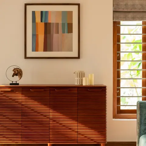 Living-room console vignette with a ribbed wood sideboard on tapered legs, a colour-block abstract framed print above, a bronze horse sculpture