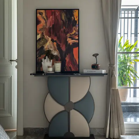 Living room console vignette with a scalloped two-tone lacquered cabinet, an abstract painting propped above it