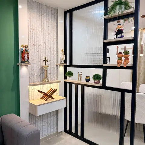 Living room corner with a black metal-framed reeded-glass partition featuring open display shelves styled with plants and figurines