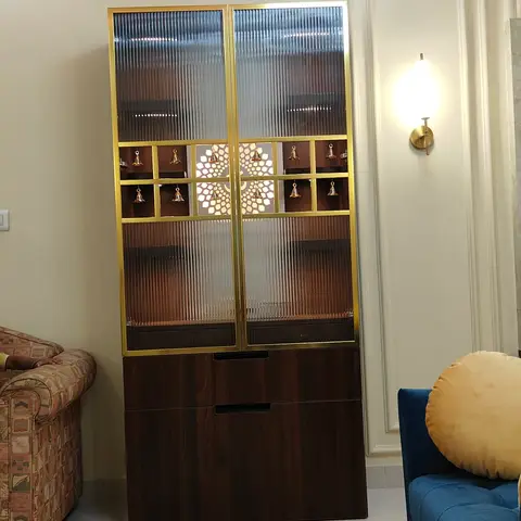 Living room corner with a brass-framed fluted-glass display cabinet holding brass temple bells