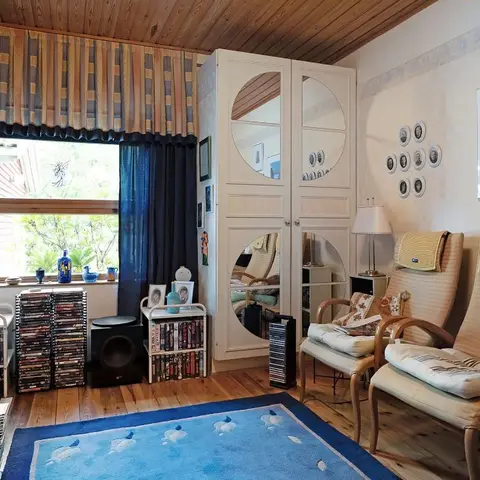 Living room corner with a mirrored wardrobe, a gallery wall of framed photos and artwork, two upholstered wood-frame armchairs