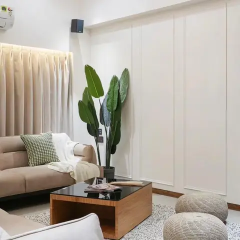 Living room corner with a wall of white panel moulding, beige velvet sofa, wood-and-glass coffee table