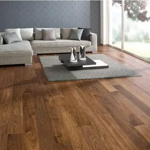 Living room corner with an L-shaped grey sectional sofa on a wide-plank walnut wood floor, a square coffee table on a grey rug