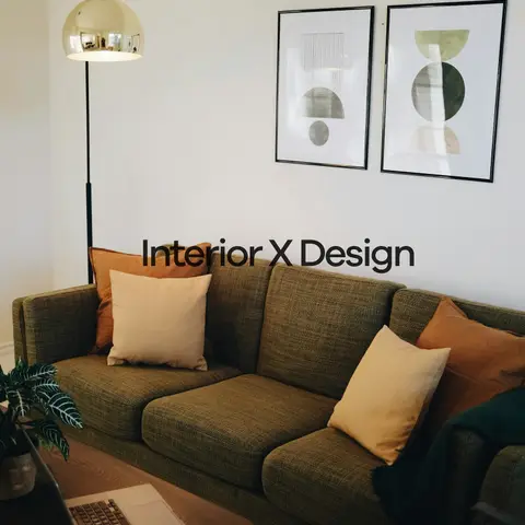 Living room corner with an olive bouclé sofa styled with mustard and rust cushions beneath a pair of framed geometric prints, and a wood coffee table.
