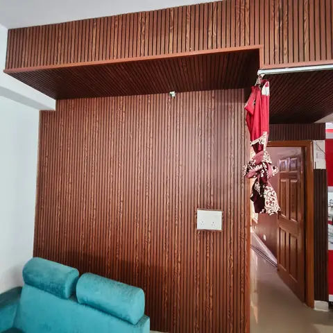 Living room corner with full-height fluted wood-slat wall panelling that wraps onto the ceiling box