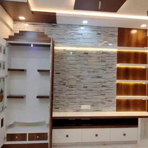 Living-room feature wall at handover: split-stone strip cladding behind a white drawer console