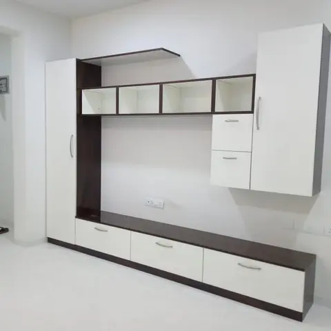 Living room feature wall combining a floating TV console with open display cubbies and a tall white-and-wenge storage cabinet, room still empty of furniture.