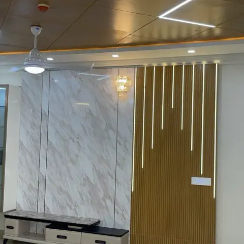 Living room feature wall pairing a white marble-look slab with a gold fluted panel carrying vertical LED strips at staggered drops