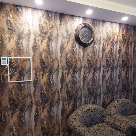 Living room feature wall with a dramatic gold-and-charcoal marbled textured wallpaper, a round bronze wall clock