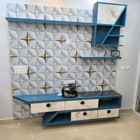 Living room feature wall with a 3D petal-pattern textured wall panel and an angular teal-blue TV console with marble-pattern drawer fronts and an asymmetric