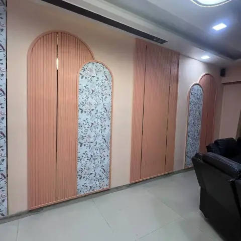 Living room feature wall with a row of arched fluted peach panels inset with floral bird wallpaper panels, an oval gold-trimmed cove ceiling light
