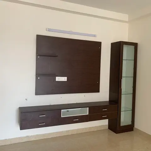 Living room feature wall with a dark walnut TV panel and floating console with drawers, paired with a tall glass-front display cabinet with glass shelving.
