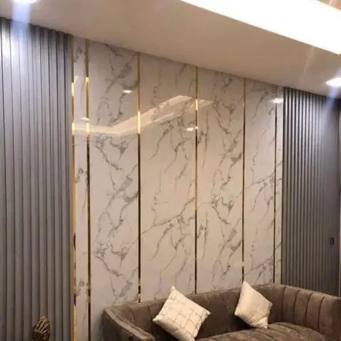 Living room feature wall with book-matched marble slabs and brass inlay strips flanked by fluted grey panelling, behind a channel-tufted taupe velvet sofa.
