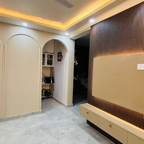Living room feature wall with dark fluted wood panelling around a backlit beige gloss TV panel, a floating console below