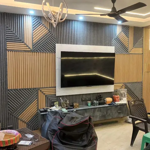 Living room feature wall with geometric grey-stone and wood fluted panelling framing a marble-bordered backlit TV unit, lit by twin sputnik chandeliers.