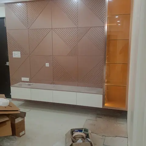 Living room feature wall with geometric rose-terracotta fluted panelling above a floating white TV console, and a backlit glass display niche beside it