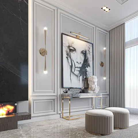 Living room feature wall with panel moulding, a marble fireplace surround, brass wall sconces flanking a portrait artwork, and a marble-and-brass console table.