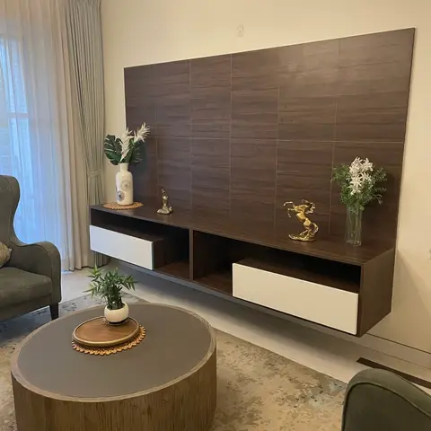 Living room floating TV console in dark wood-look tile cladding with brass horse and figure sculptures