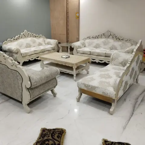 Living room furnished with a carved cream baroque-style sofa set and matching coffee table on a marble floor.