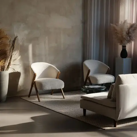 Living room in warm afternoon light with two boucle-and-wood accent chairs and a cream sofa on a jute rug