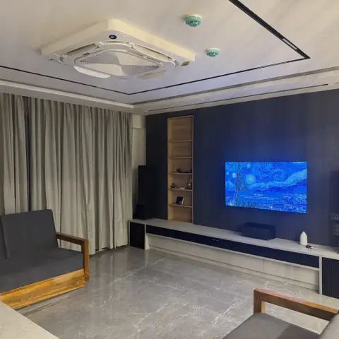 Living room lit mainly by the TV showing a Starry Night screensaver on a charcoal fabric-clad wall, with tower speakers either side