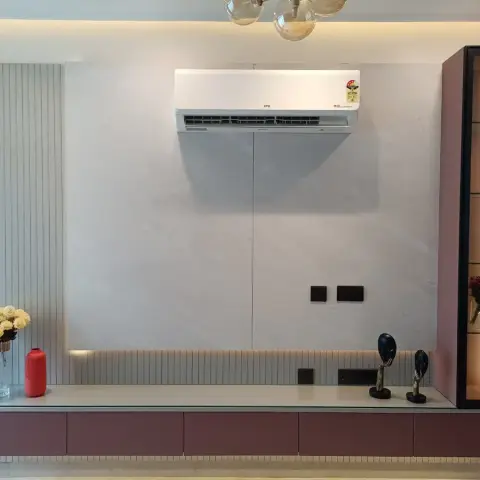 Living room media wall where a pale marble-look slab meets grey fluted panelling, above a long wine-coloured handleless drawer console lit by an LED strip in