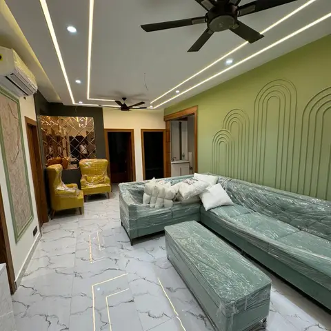 Living room mid-handover with plastic-wrapped sage green sectional and mustard armchairs, a fluted arch-pattern green feature wall