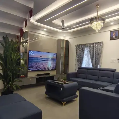 Living room of a newly occupied flat with a navy leatherette sofa set and ottoman on gold legs