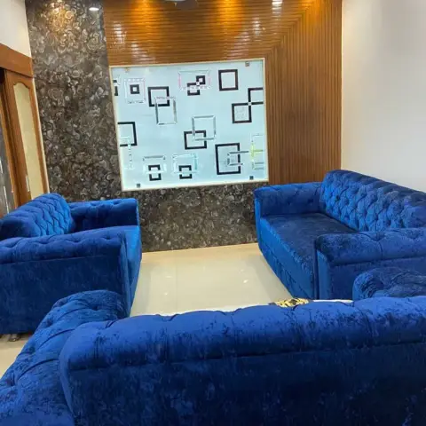 Living room ringed by royal-blue crushed-velvet tufted sofas facing a feature wall of vertical wood slats