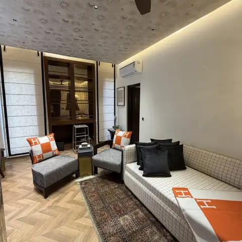Living room seating nook with a celestial-motif textured ceiling, herringbone parquet flooring, a checked sofa styled with orange-and-white branded cushions