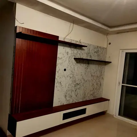 Living room TV feature wall combining dark maroon fluted wood panelling with white-veined marble cladding and a floating maroon-and-white TV console