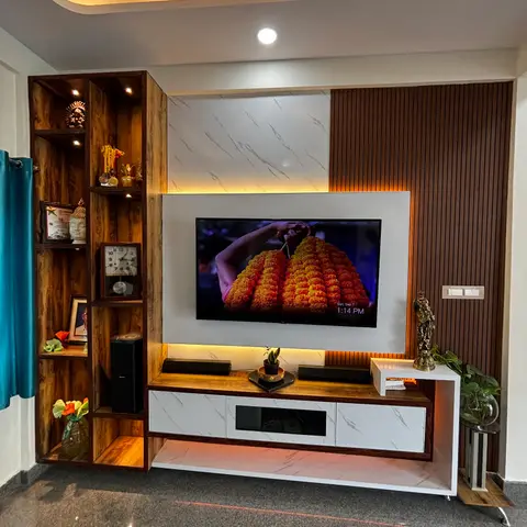 Living room TV feature wall combining marble cladding and vertical fluted wood panelling, flanked by an open display shelving unit with framed photos and curios