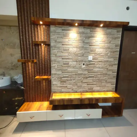 Living room TV feature wall combining a stacked-stone-look tile backdrop with a vertical fluted wood panel and a backlit wood floating unit with white